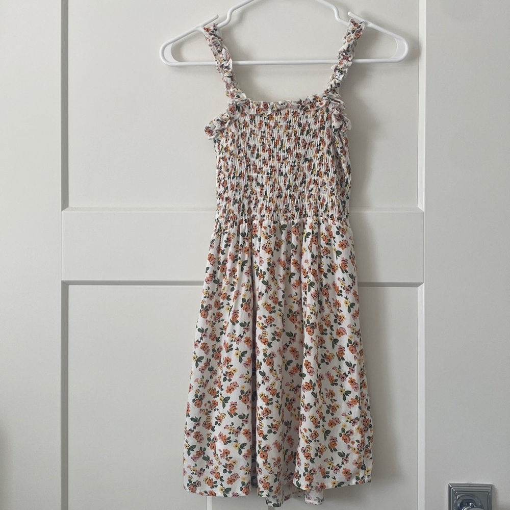 white dress with orange, pink, yellow flowers and green leaves.
